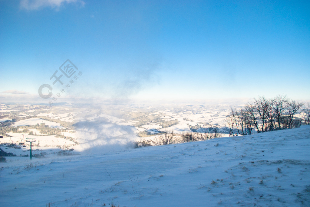 风吹雪覆盖的山峰和远处的一座木房子山中的雪风