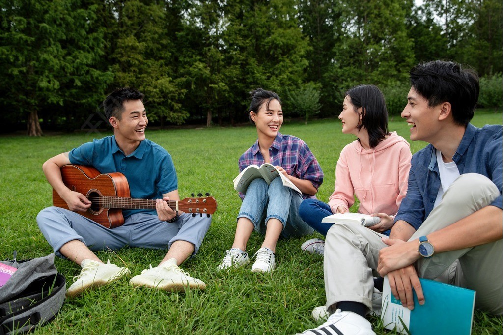 快樂的大學生在草地上彈吉他唱歌