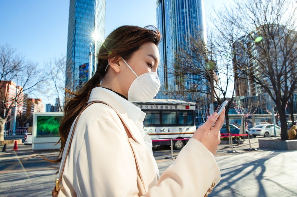 戴口罩的青年女人看手機