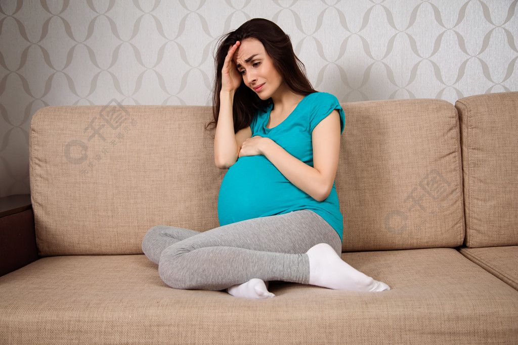 怀孕妇女的抑郁症一个年轻的孕妇坐在沙发上哭着回家