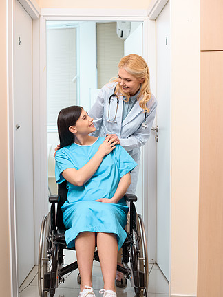 成熟产科妇科医生骑在产妇医院轮椅上的孕妇和支持她