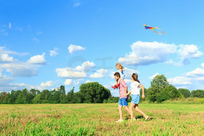 母亲、父亲和女儿正在田野里放风筝。回来了