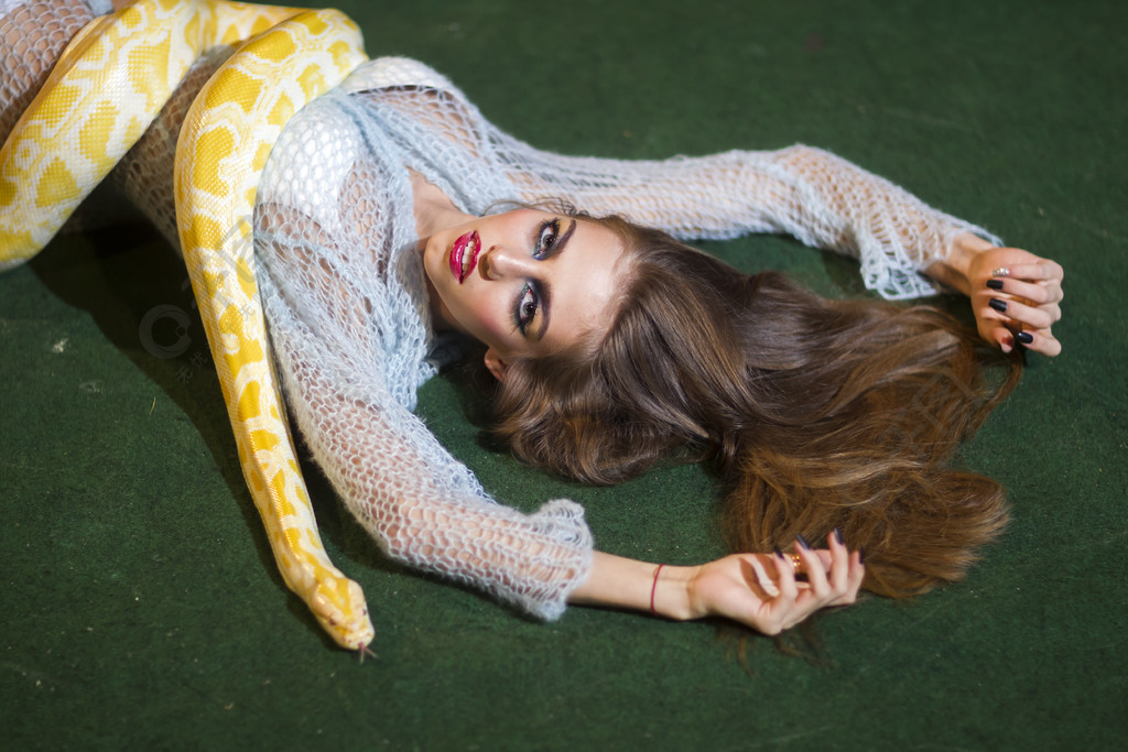 性感女人用白化蟒蛇放松蛇在长头发的女人身上爬行化妆脸和黄色蛇的