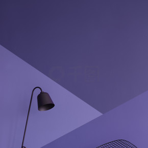 不对称的紫色墙壁在现代客厅内部与金属灯和黑扶手椅在格子地板。真实照片