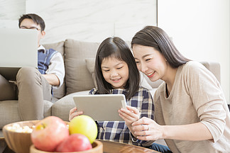 快乐的亚洲家庭在客厅的沙发上共度时光。家庭和家居概念