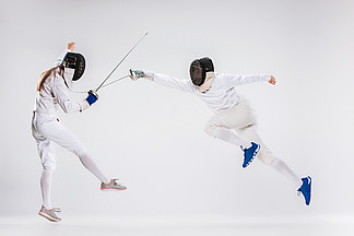 男人和女人穿着击剑适合用刀攻击灰色练习