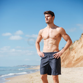 自信健壮的年轻男人站在海边