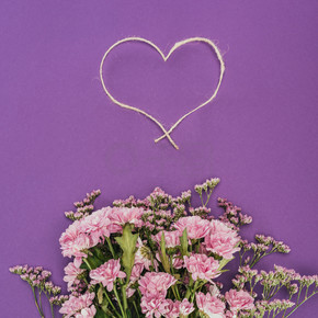 紫罗兰色的美丽的粉红色的花朵和心形的绳子花束