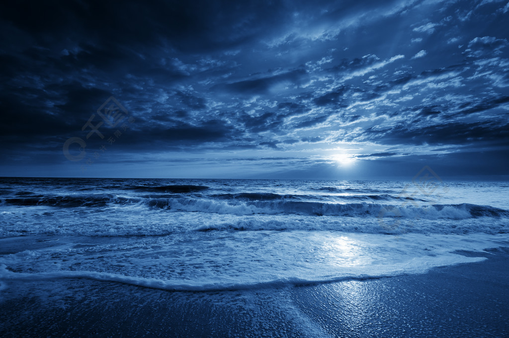 午夜蓝沿海月亮与戏剧性的天空和翻滚的波涛