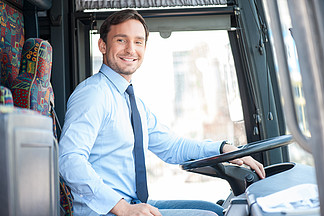 Attractive young man <i>is</i> driving a public transport