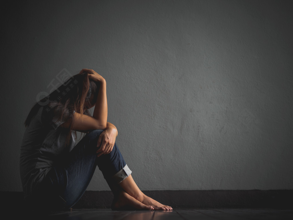 悲伤的女人抱着她的膝盖和哭泣悲伤的女人独自坐在空荡荡的房间