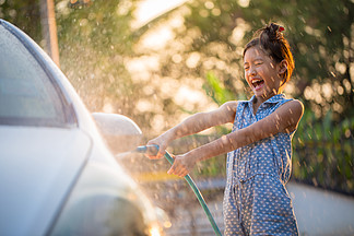 快乐的亚洲女孩洗车水溅和阳光在家里