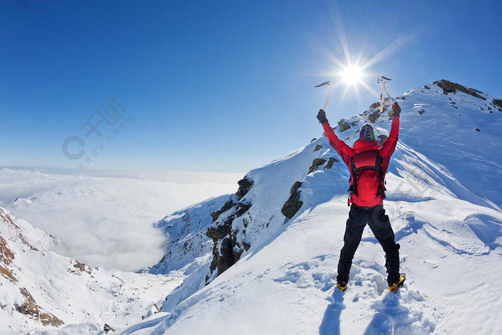 登山运动员到达顶部的雪山在阳光明媚的冬天