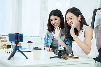 在社交媒体上，有魅力的亚洲女人通过智能手机在线销售产品。年轻的女性时尚博客在网上直播服装.