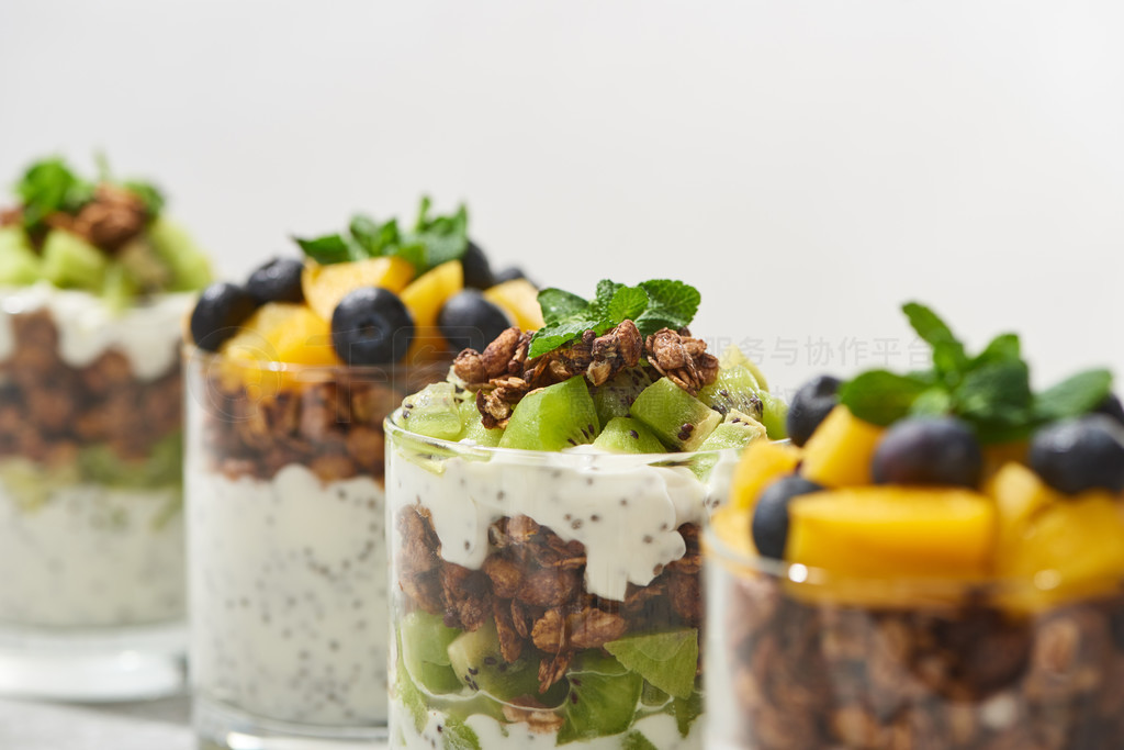 selective focus of fresh granola with kiwi and canned peach with blueberries isolated on white