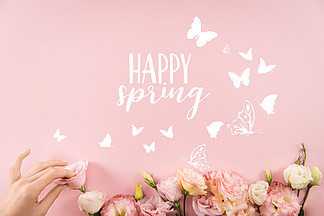 手安排美丽的嫩花与愉快的春天标志和蝴蝶在粉色背景下被隔绝的上部看法