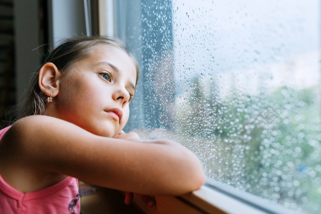 小女孩忧心忡忡地望着窗玻璃里的雨滴很多悲伤童年的概念形象