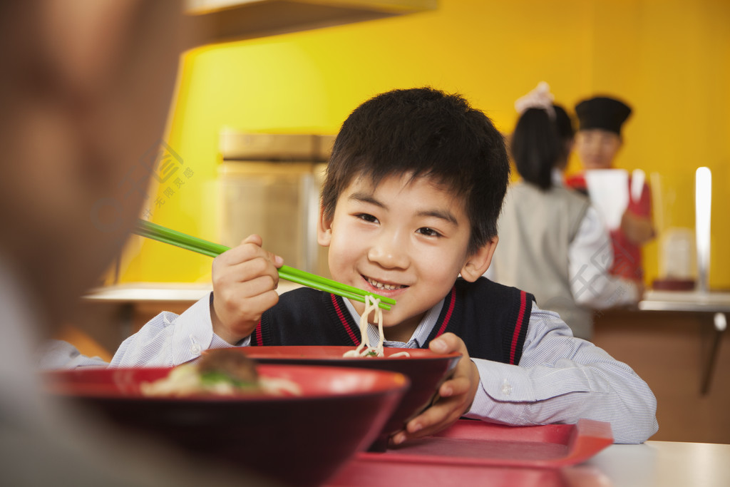 學校的男孩在學校的食堂吃麵條