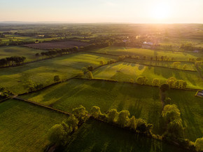 爱尔兰无边无际的郁郁葱葱的牧场和农田的鸟瞰图。美丽的爱尔兰乡村，有绿色的田野和草地。日落时分的乡村景观.
