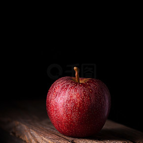 一个黑色背景的红苹果，垂直的