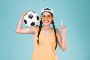 球迷体育妇女微笑和快乐, 拿着一个足球, 庆祝点一手指向上优胜者标志
