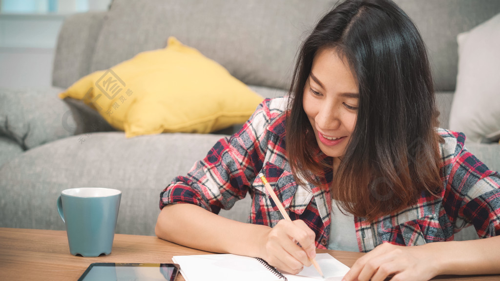 亚裔女学生在家做作业,女同学用平板电脑在客厅的房间里找