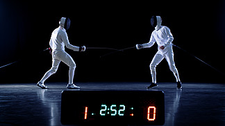 冠军两个专业充分装备击剑与战斗在箔计分板保持同时命中的成绩。拍摄于孤立的黑色背景.