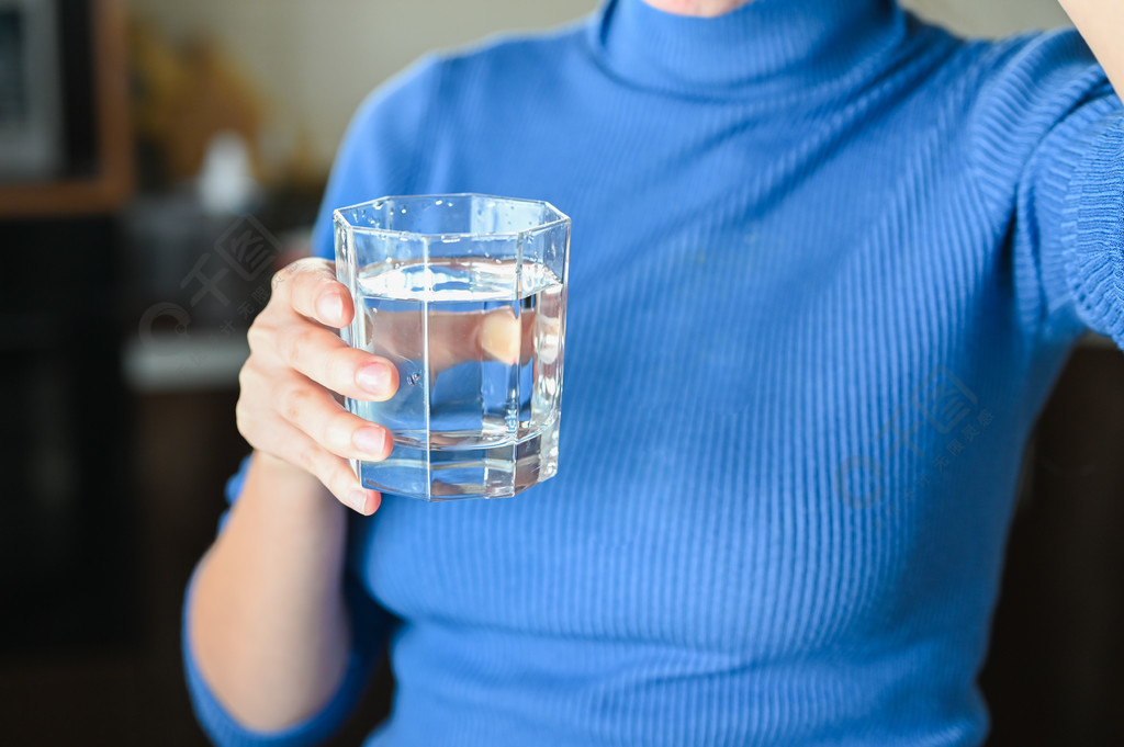 喝大量的水从病毒，Covid-19大流行的大肠癌。女孩从杯子里喝水.