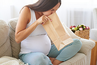 怀孕的女人觉得恶<i>心</i>使用纸袋空气