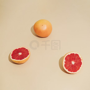 葡萄柚的阳光照射最小的水果成分,在沙色背景上带有阴影。夏季创意理念
