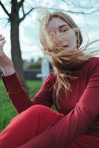 一个红衣金发女孩坐在城市里,她的头发被风吹散